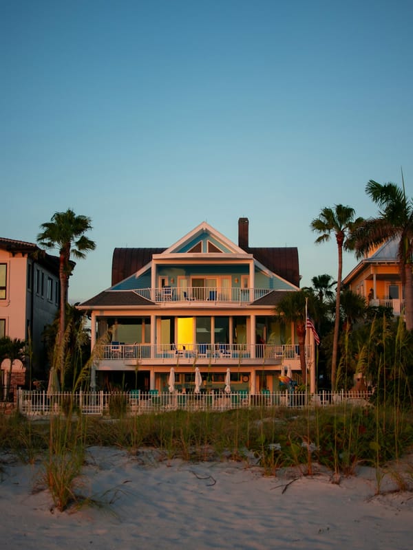 A three-story beach house with wraparound porches and palm trees at golden hour on Clearwater Beach