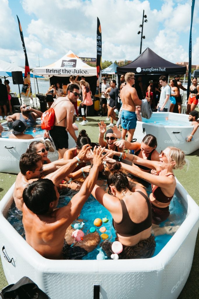 Guests high-fiving in a cold plunge tub at an AltSocial Wellness Club event at Armature Works in Tampa